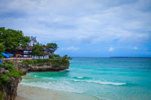 马卡萨Monoloog Hotel Makassar的享有海滩美景,设有房屋和大海