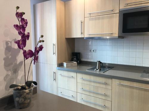 大加那利岛拉斯帕尔马斯Sweet Apartment Las Canteras的厨房配有白色橱柜和紫色花瓶