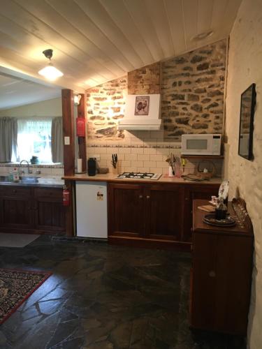 斯特拉萨尔宾Gasworks B&B Cottages的厨房配有木制橱柜和石墙