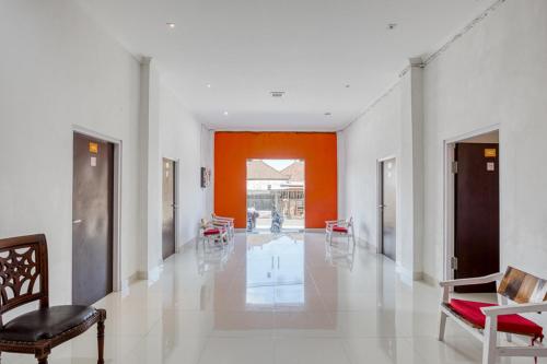 苏卡瓦提RedDoorz near Bali Zoo Ubud的走廊上设有橙色和白色的墙壁和椅子
