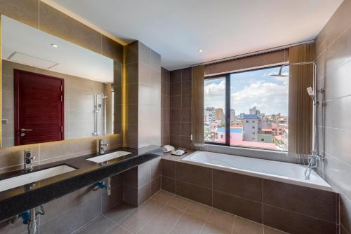 金边Residence 105 Hotel and Apartment的一间带两个盥洗盆、浴缸和窗户的浴室