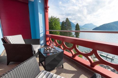 菲茨瑙Hotel Vitznauerhof - Lifestyle Hideaway at Lake Lucerne的阳台配有桌椅,享有水景。