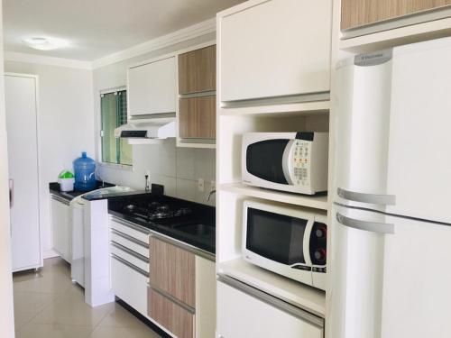 邦比尼亚斯Apartamentos Mediterrâneo Home Club的厨房配有白色橱柜和微波炉