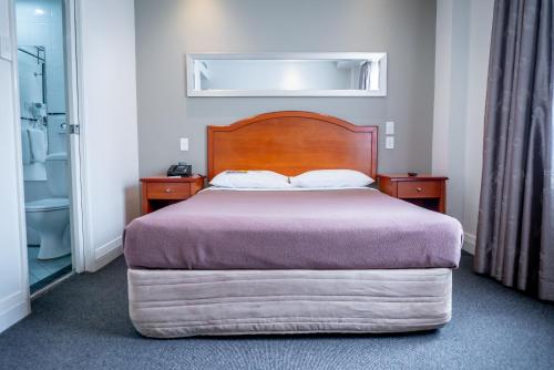 悉尼悉尼南部大酒店的一间卧室配有一张带木制床头板的床