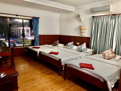 暹粒Jasmine Lodge Siem Reap的一间卧室配有三张床和红色枕头。
