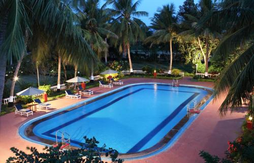 坦贾武尔GReaT Trails Riverview Thanjavur By GRT Hotels的度假村内一座种有棕榈树的大型游泳池
