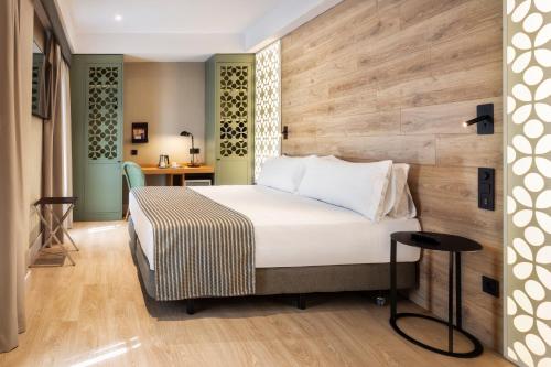 塞维利亚加泰罗尼亚圣胡斯塔酒店的一间卧室设有一张床和木墙