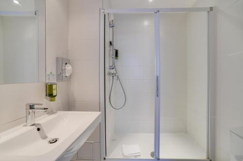 布洛涅-比扬古Parici Hôtel Boulogne Billancourt的带淋浴和盥洗盆的白色浴室