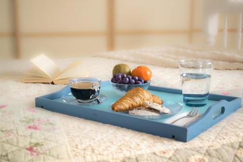 卡拉马基亚历山德罗斯公寓酒店的床上的蓝色托盘,包括食物和饮料