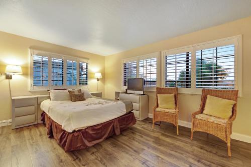 圣克鲁兹Boardwalk Dream的一间卧室配有一张床、两把椅子和窗户