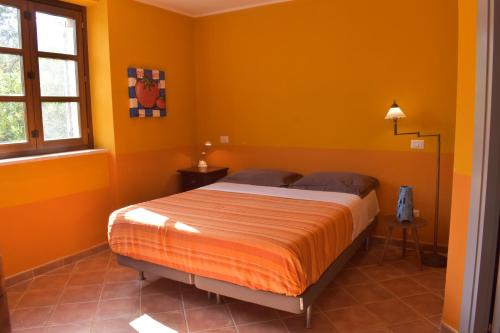 卡拉塞Casa Ciao Bella - Apartment Sunshine with shared pool的一间拥有橙色墙壁的卧室和一张位于客房内的床