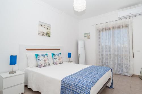 波尔蒂芒Apartamentos Castelos da Rocha的白色卧室配有一张带蓝色枕头的大床