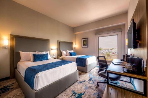 埃莫西约Comfort Inn Hermosillo Aeropuerto的酒店客房设有两张床和电视。