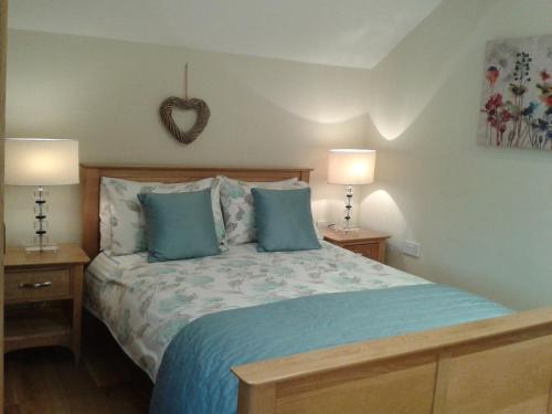 布劳顿弗内斯通瑟维农场度假屋的一间卧室配有一张带蓝色枕头的床和两盏灯。