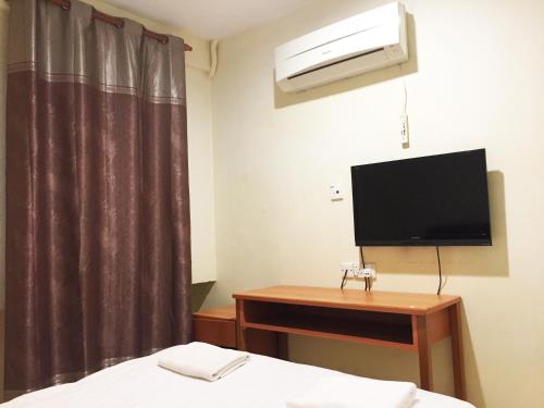 米里HK Inn Hua Kiew Inn的一间卧室配有一张床、一台电视和一张书桌
