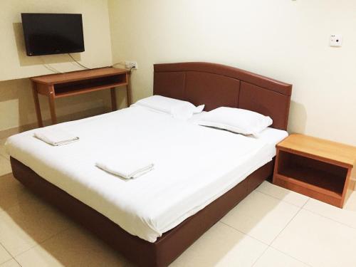 米里HK Inn Hua Kiew Inn的一间卧室配有一张带电视和桌子的床。