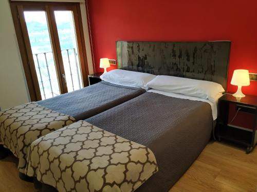 昆卡阿里萨克旅馆的一间卧室设有两张床和红色的墙壁