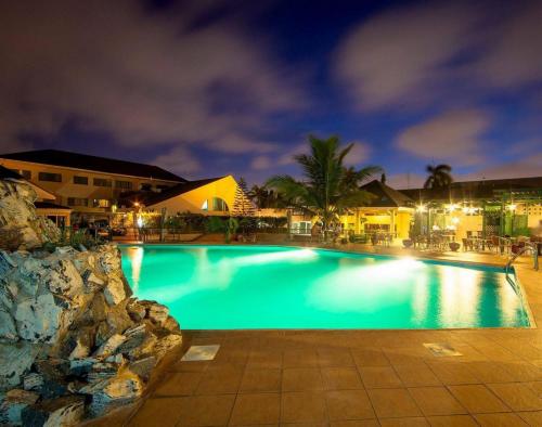 阿克拉Alisa Hotel North Ridge的夜间大型游泳池,灯光照亮