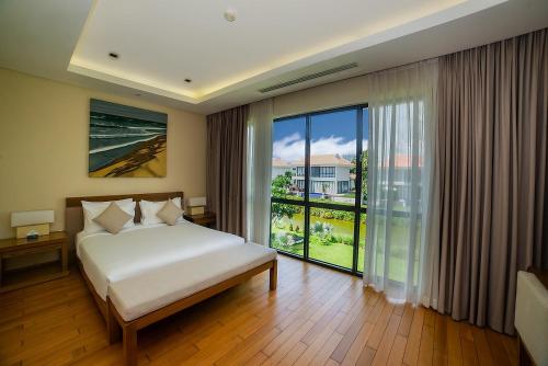 岘港The Ocean Villas Managed by The Ocean Resort的一间卧室设有一张床和一个大窗户