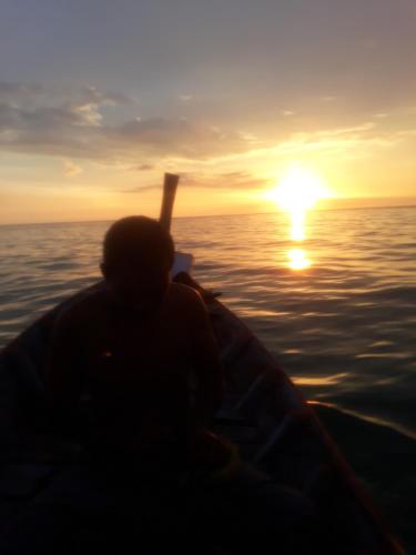 高兰Andaman Bay House的日落时在海上的船上的人