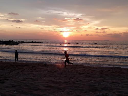 高兰Andaman Bay House的日落时在海滩上跑步的两个人