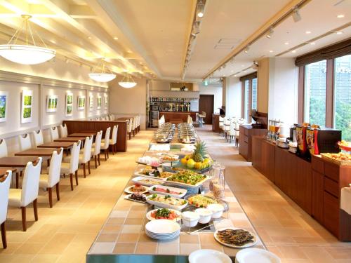 东京Sotetsu Grand Fresa Tokyo-Bay Ariake的长长的用餐室,配有长桌子,摆放着食物
