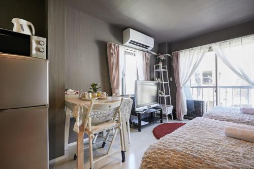 东京Akabane TK Building 203的小房间设有桌子、床和电视