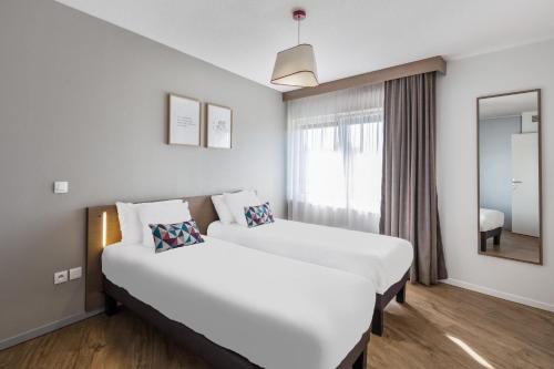米卢斯Appart'City Confort Mulhouse的酒店客房,设有两张床和镜子