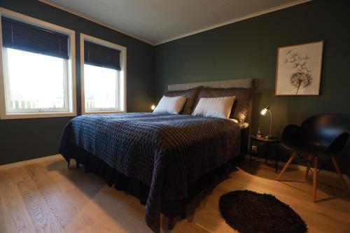 HamarvikModern apartment with seaview的一间卧室配有一张蓝色棉被和两个窗户。