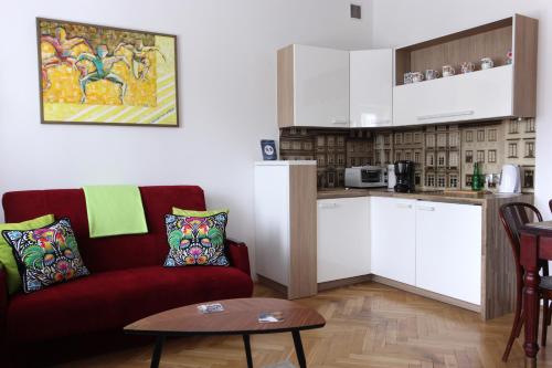 华沙克拉克夫郊区街“昼夜”公寓的一间带红色沙发的客厅和一间厨房