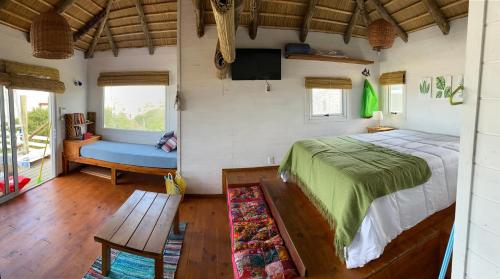 德尔迪阿布罗角Cabañas Punta Papaya的一间卧室配有一张床、一张长凳和一台电视。