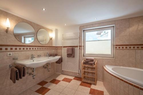 迈尔霍芬AlpenLiving的一间带水槽和浴缸的浴室以及窗户。