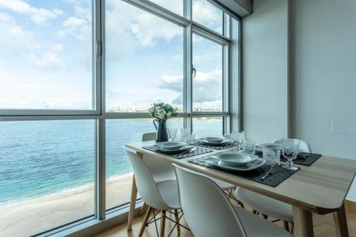 拉科鲁尼亚APARTAMENTO CON INCREIBLES VISTAS A LA PLAYA DE RIAZOR的一间配备有桌椅的海景用餐室