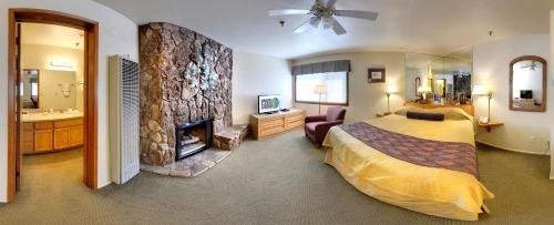 大熊湖雪湖度假山林小屋的一间卧室设有一张大床和一个壁炉