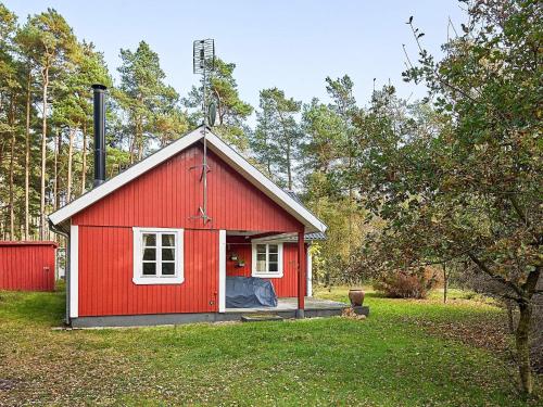 维斯特索马肯6 person holiday home in Aakirkeby的院子里有白色窗户的红色棚子