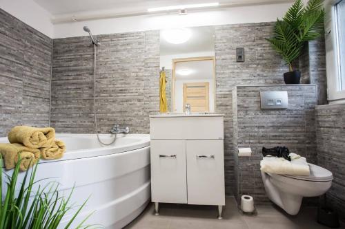 佩奇Csigaház Apartman的浴室配有白色浴缸和卫生间。