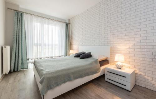 华沙Galeria Rondo Wiatraczna Apartments的卧室配有床和白色砖墙