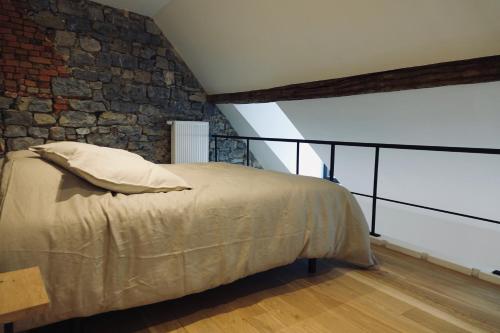 马尔什昂法梅讷Le Clocher - Résidence Le Cercle的一间卧室设有一张床和石墙