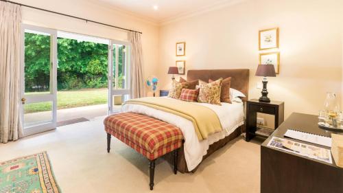 BalgowanArum Hill Lodge的一间卧室配有一张床、一张书桌和一个窗户。