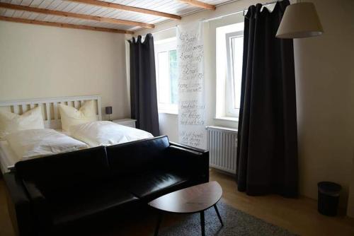文西德尔Hotel Berggasthof Waldlust的一间卧室配有一张床和一张黑色皮沙发