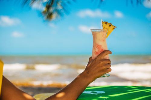 霍普金斯Hopkins Bay Belize a Muy'Ono Resort的一个人在海滩前喝上一杯