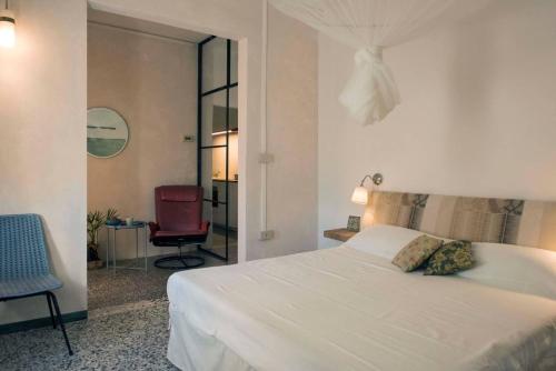 泰塞拉CASA DI ROBY - VENICE AIRPORT的卧室配有白色的床和红色椅子