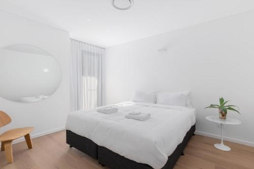萨维特尔13 First Avenue Sawtell的白色卧室配有一张大床和一张桌子