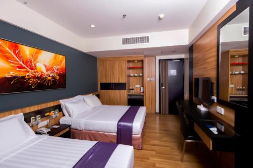 拉布安Mariner Hotel Labuan的一间酒店客房,设有两张床和电视