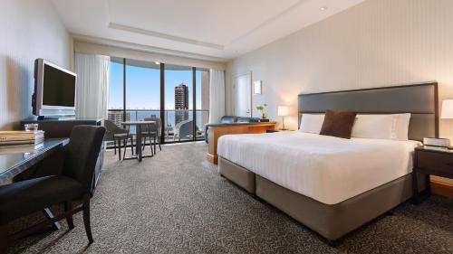 黄金海岸Oaks Gold Coast Hotel的酒店客房配有一张床、一张书桌和一台电视。