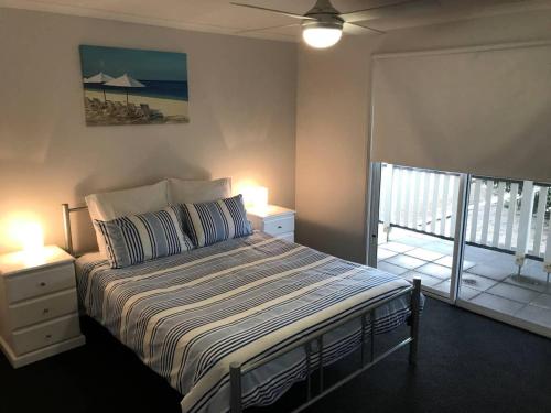 Port MoontaMoontana的一间卧室配有一张带两盏灯的床和一个阳台