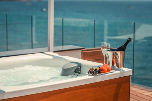 贾迪尼-纳克索斯Nautilus Hotel的浴缸配有一瓶葡萄酒和玻璃