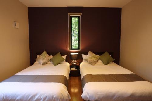 本部Tabinoteitaku Okinawa Bise HOMANN CONCEPT的带窗户的客房内的两张床