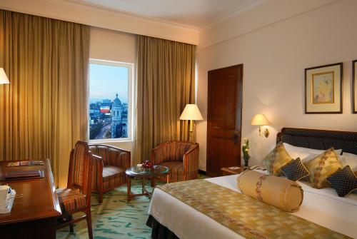 加尔各答Peerless Hotel Kolkata的配有一张床、一张书桌和一扇窗户的酒店客房