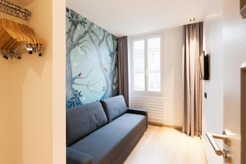 巴黎Hôtel So Marais的客厅配有蓝色的沙发和壁画